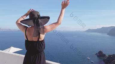 圣托里尼岛旅游走火山口视图爱琴海海年轻的女人参观旅行目的地<strong>地标性建筑</strong>穿红色的衣服夏天假期aio圣托里尼岛希腊岛屿希腊欧洲